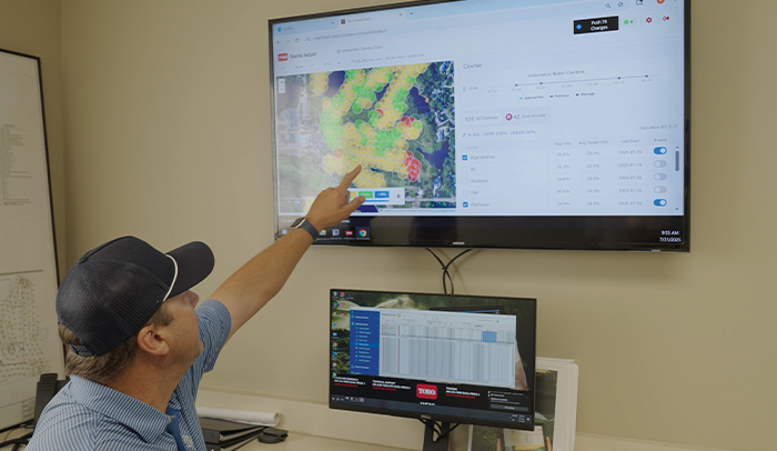 Someone pointing at a monitor showing a map of sprinklers on a golf course.